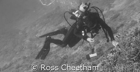 a diver playing with a clown fish with a wide angle lens on by Ross Cheetham 